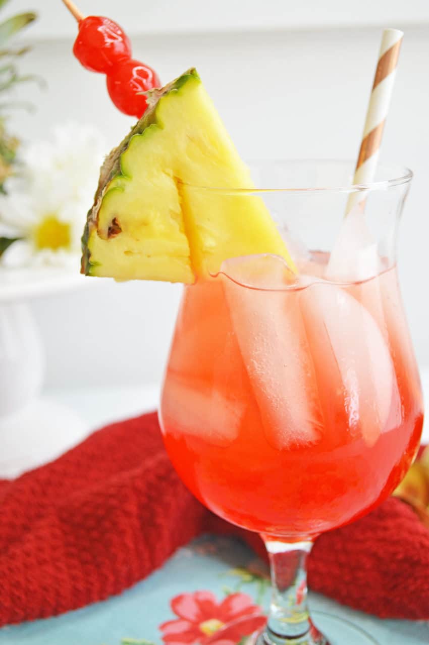 Closeup of Pineapple Cherry Rum Punch with gold stripe paper straw