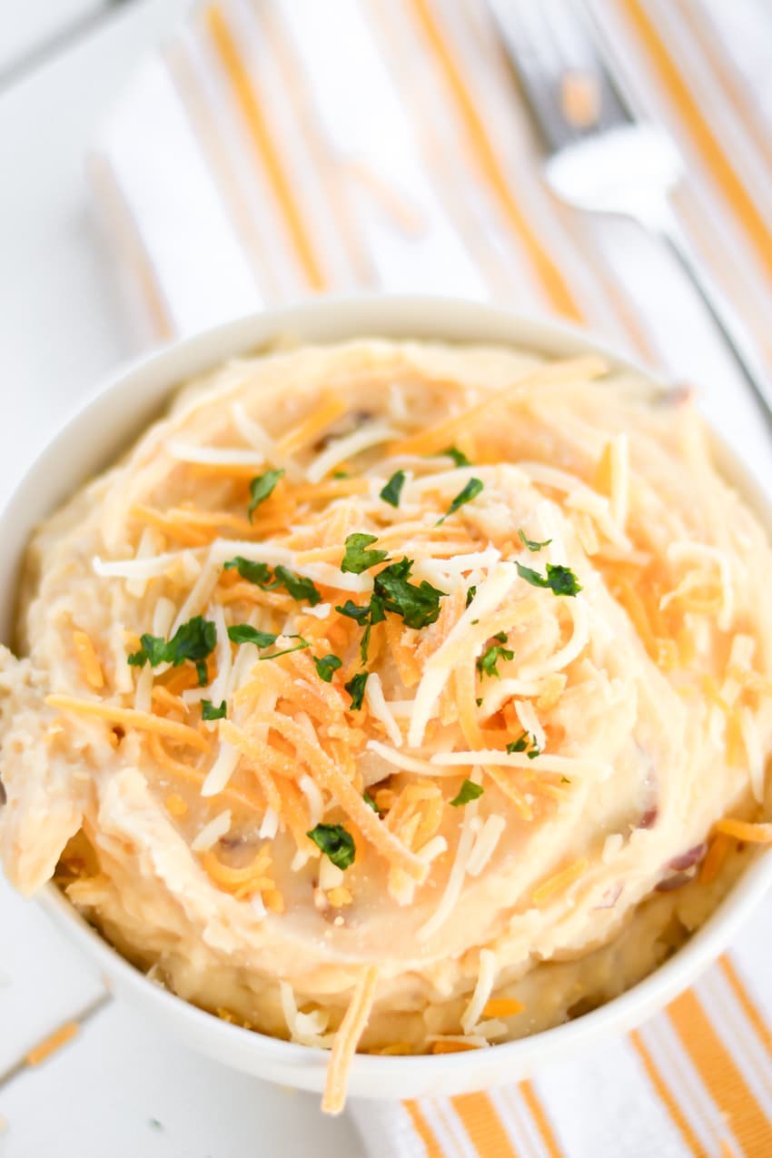 Bowl of garlic cheddar mashed potatoes topped with shredded cheese