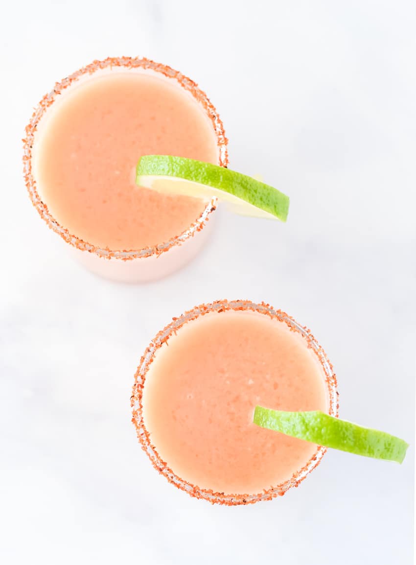 View of two frozen guava margaritas with lime from above