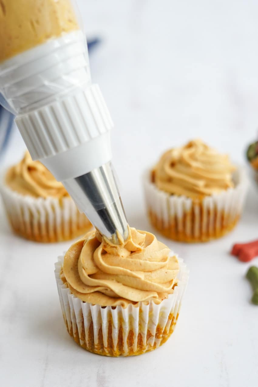 Frosting pumpkin pupcakes with peanut butter cream cheese frosting