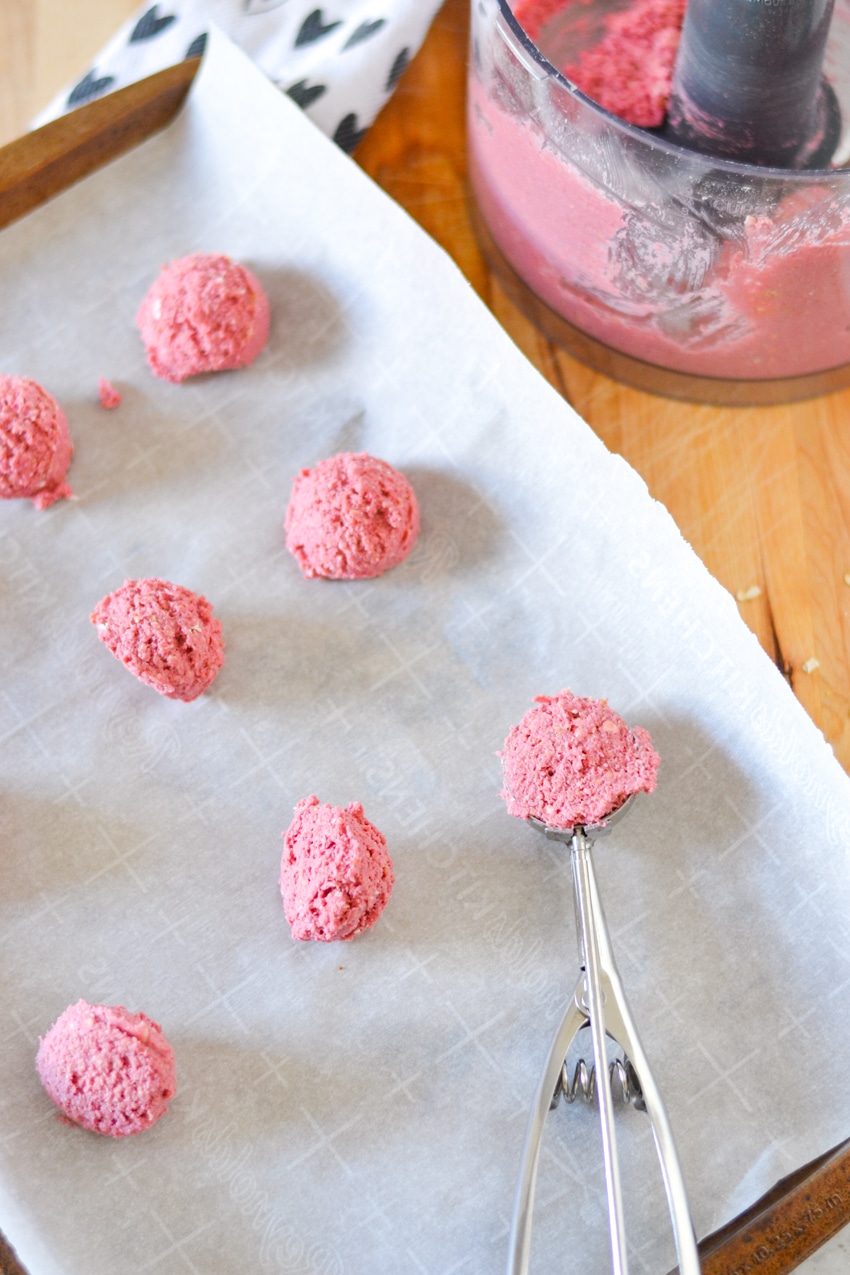 Pink dog treat dough spooned out on parchment paper
