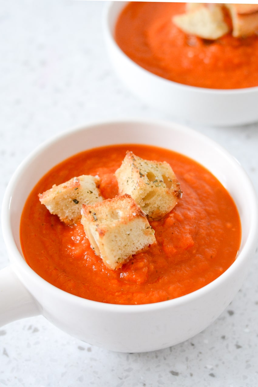 White bowl filled with rustic homemade tomato soup and large homemade croutons on top