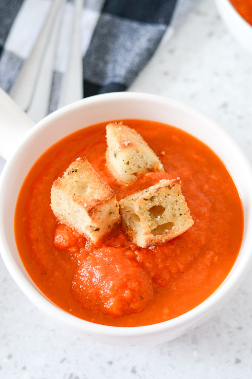 rustic tomato soup in a white bowl with large croutons on top