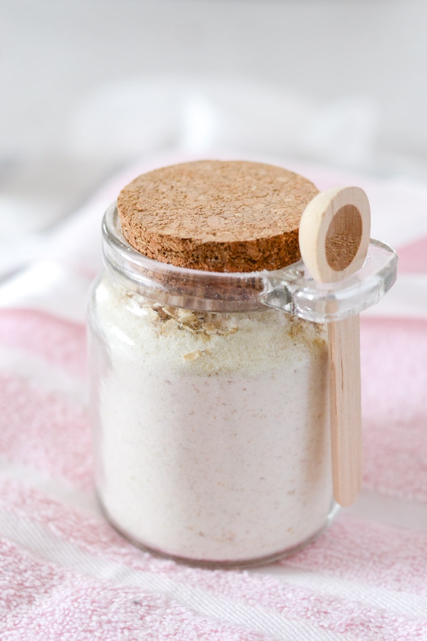 Glass jar with cork lid filled with homemade milkbath powder on pink towel