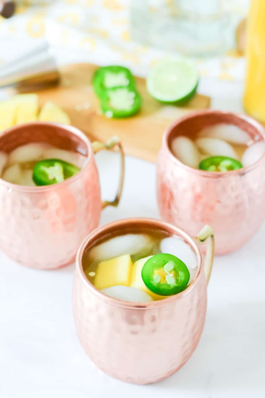 3 copper mugs with jalapeños floating on ice