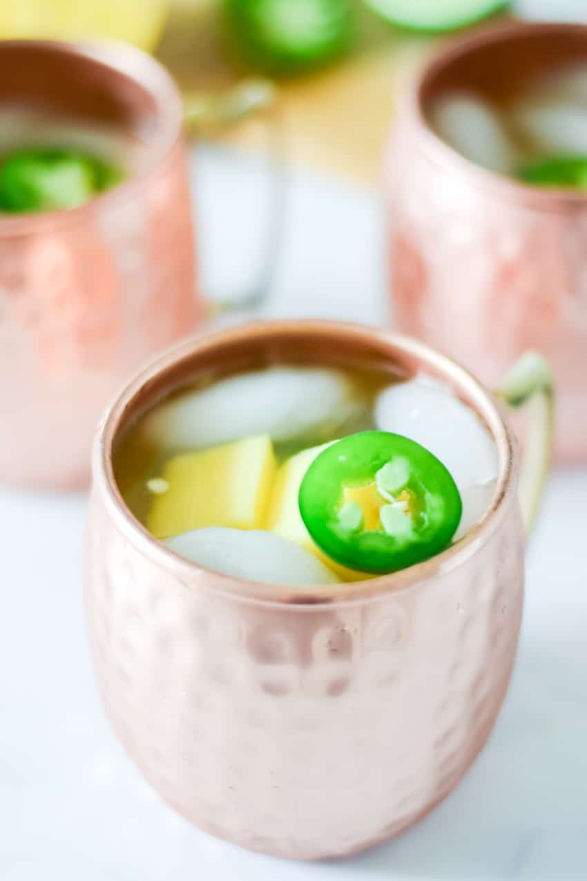 Close up of jalapeño and mango floating in copper mug.