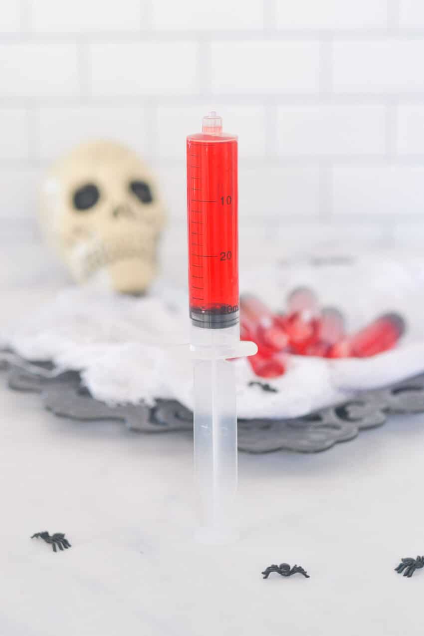 One plastic syringe filled with red Jello standing on it's end