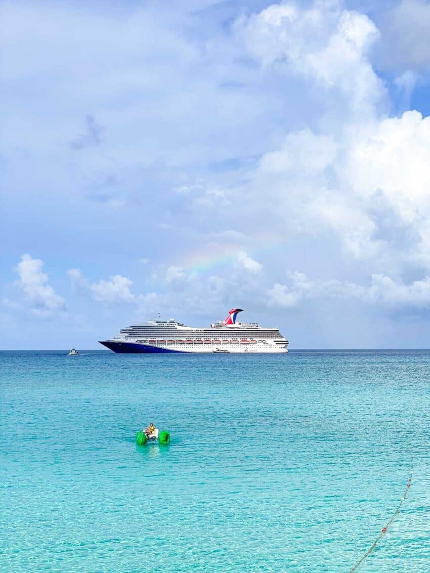 The Carnival Sunrise ship sitting off shore at Half Moon Cay, Bahamas, with a very slight rainbow shining over it. 