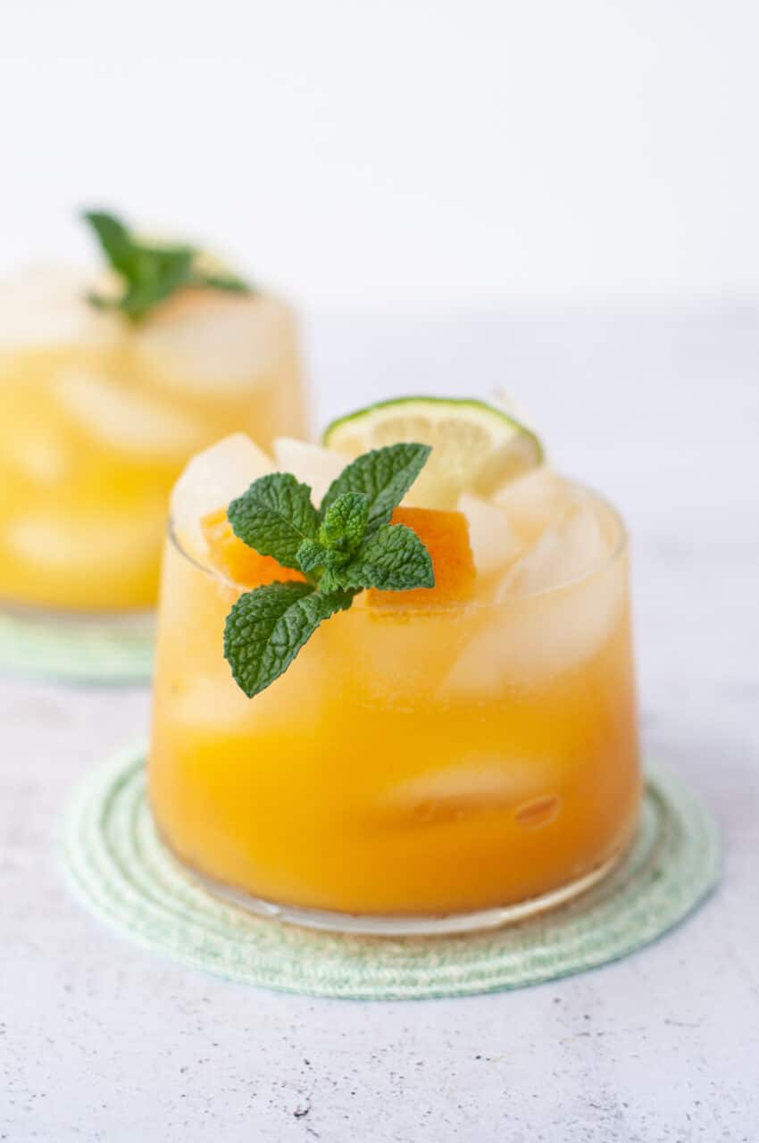 Two glasses filled with passion fruit mojito with a white background