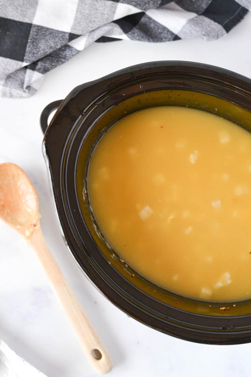 Look inside crockpot filled with uncooked ingredients for potato soup