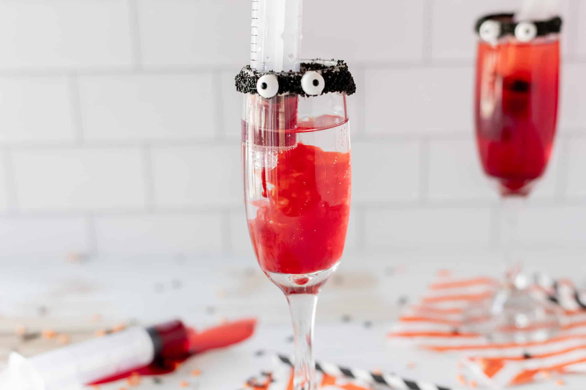 Syringe filled with grenadine in a champagne glass of sprite to make a monster mocktail